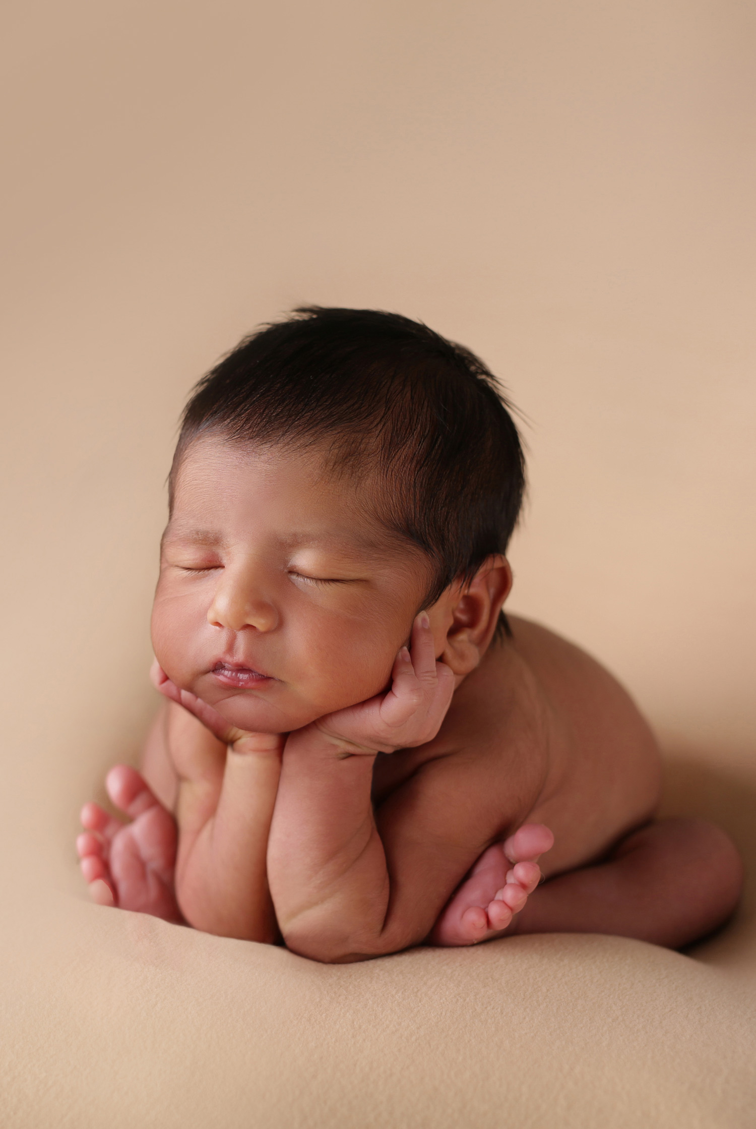 newborn baby in tan background froggy pose