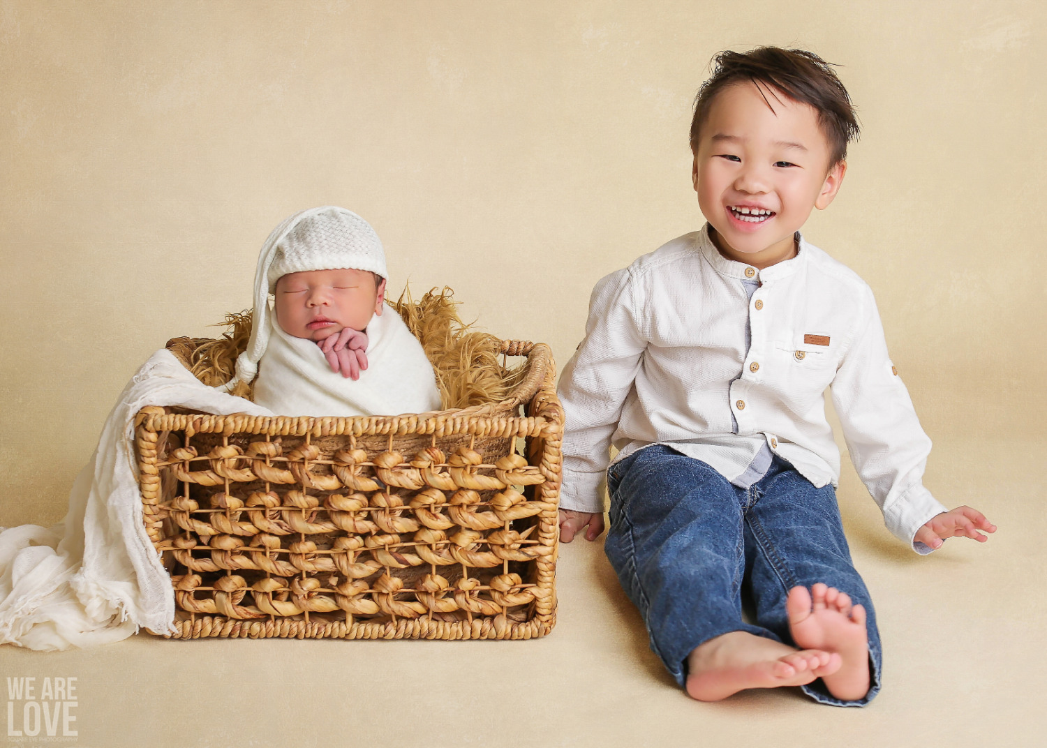 newborn baby with brother on tan background